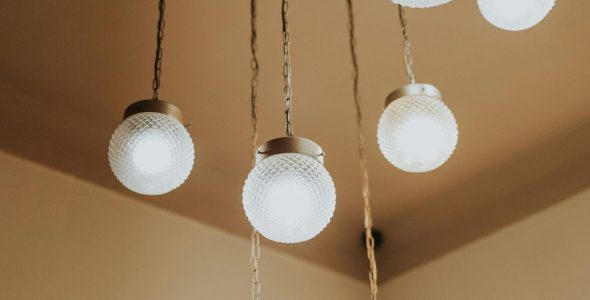 Stylish glass chandeliers with brass accents hanging from ceiling in a minimalist setting.