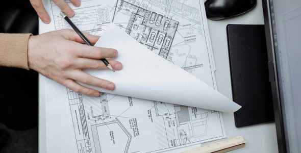 High-angle view of an architect reviewing construction drawings on a desk in an office.